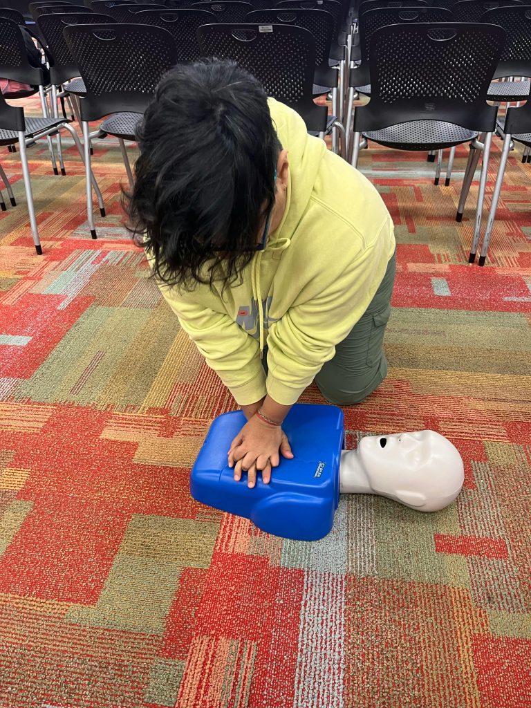 Gallary Individual practicing CPR on a training manikin in a classroom setting.